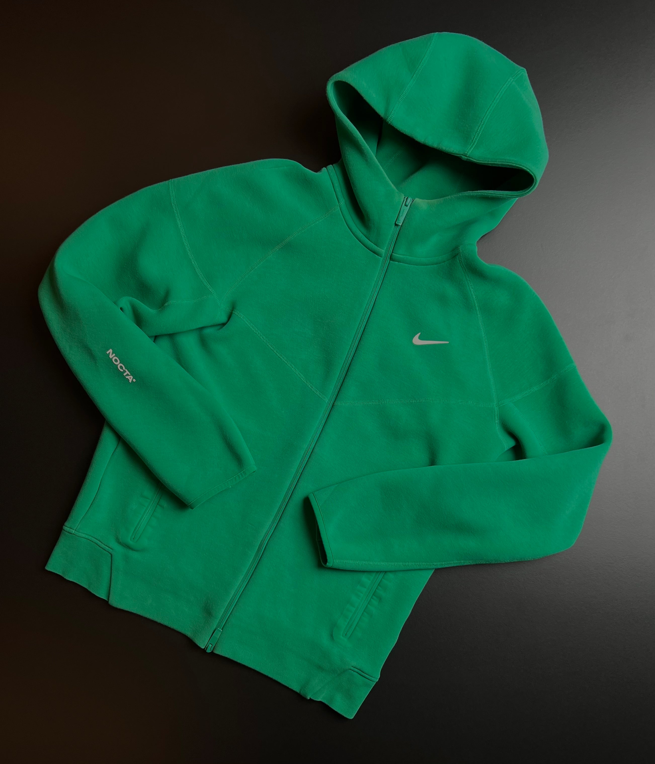 Green Nike NOCTA tracksuit in size M displayed on a mannequin, showcasing its sporty design and vintage style.