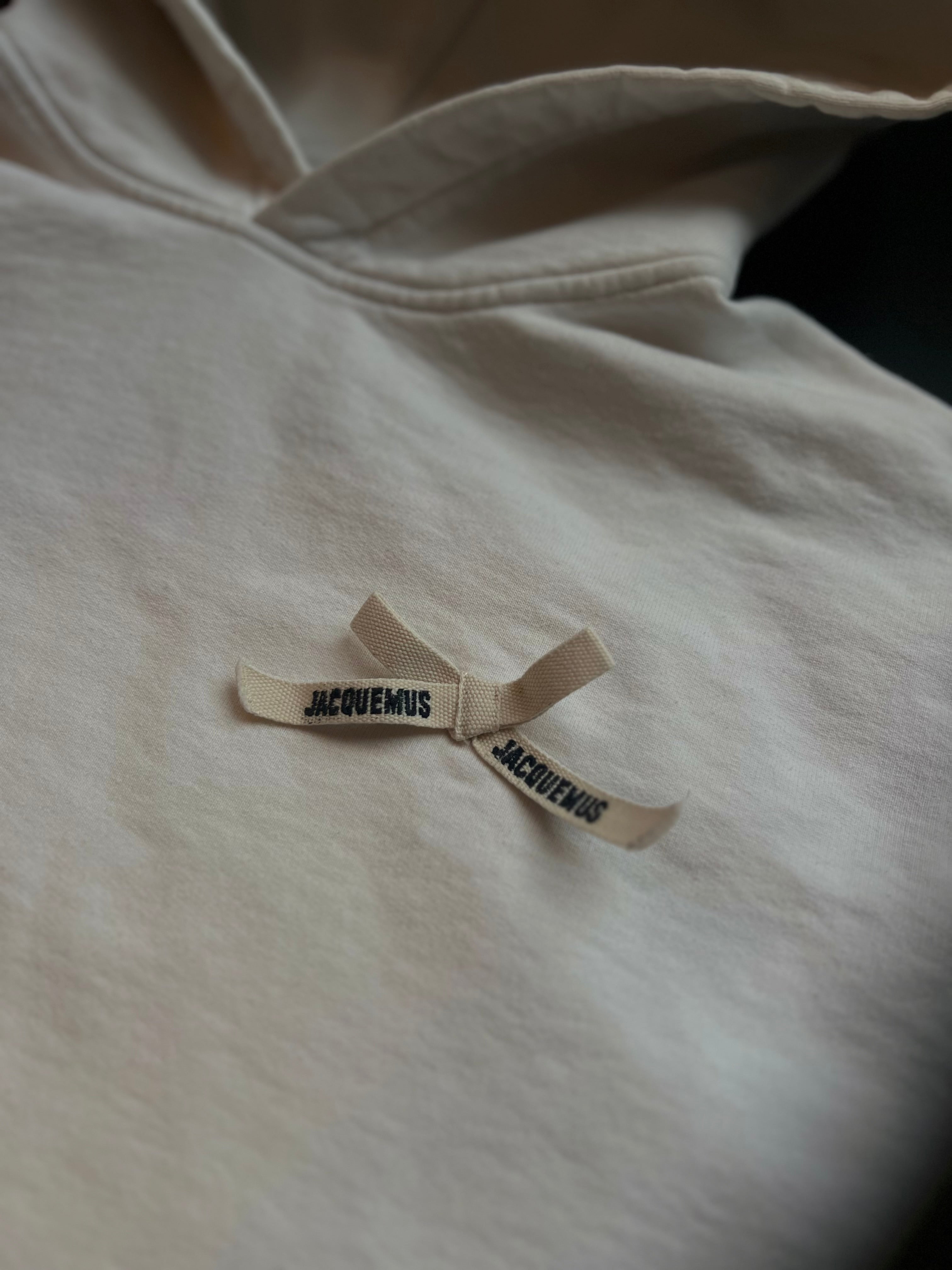 Cream white Jacquemus hoodie in size M, featuring a relaxed fit and minimalistic design displayed on a hanger.